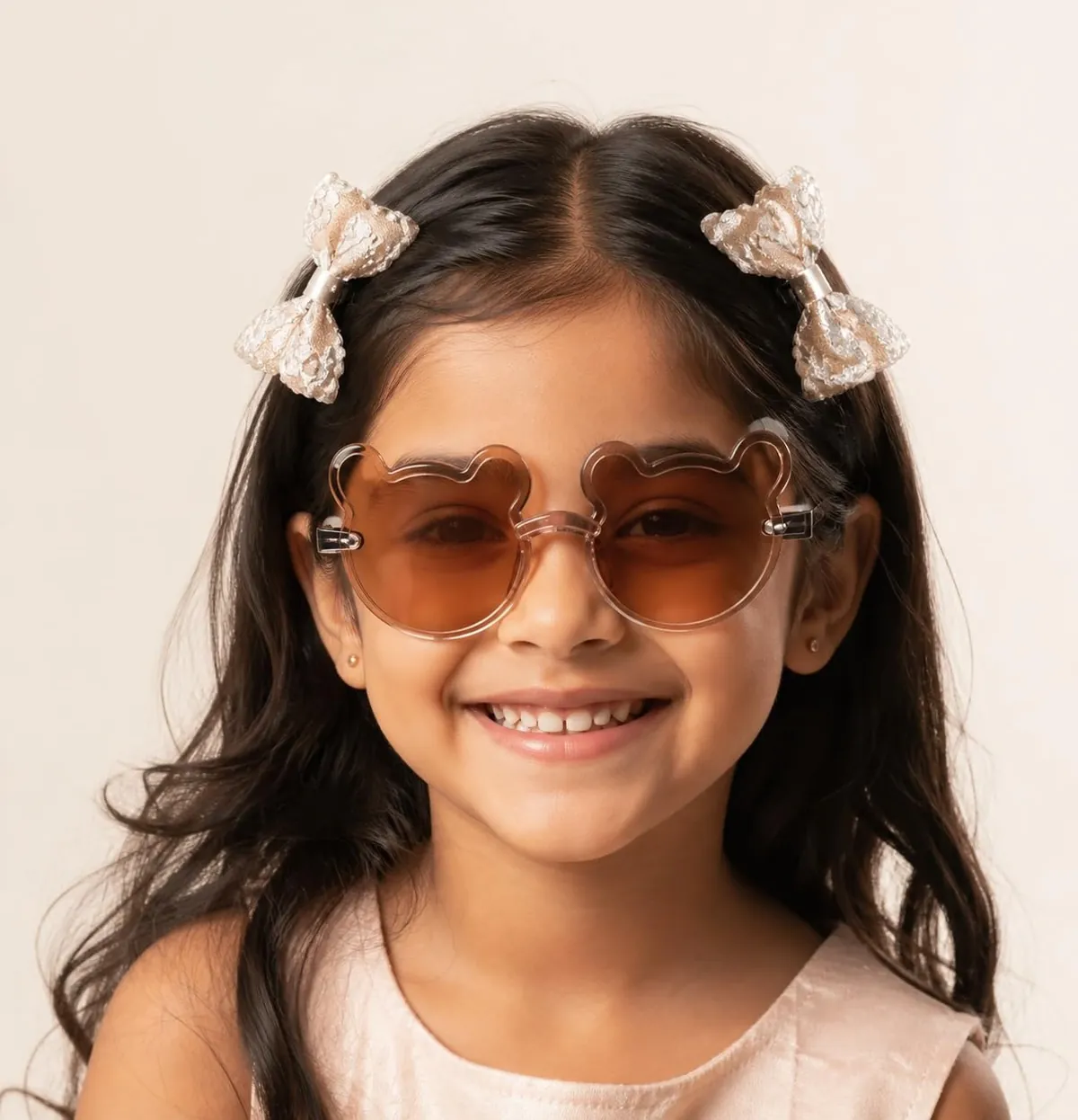 A girl smiling in brown bear sunglasses with lace bows in her hair