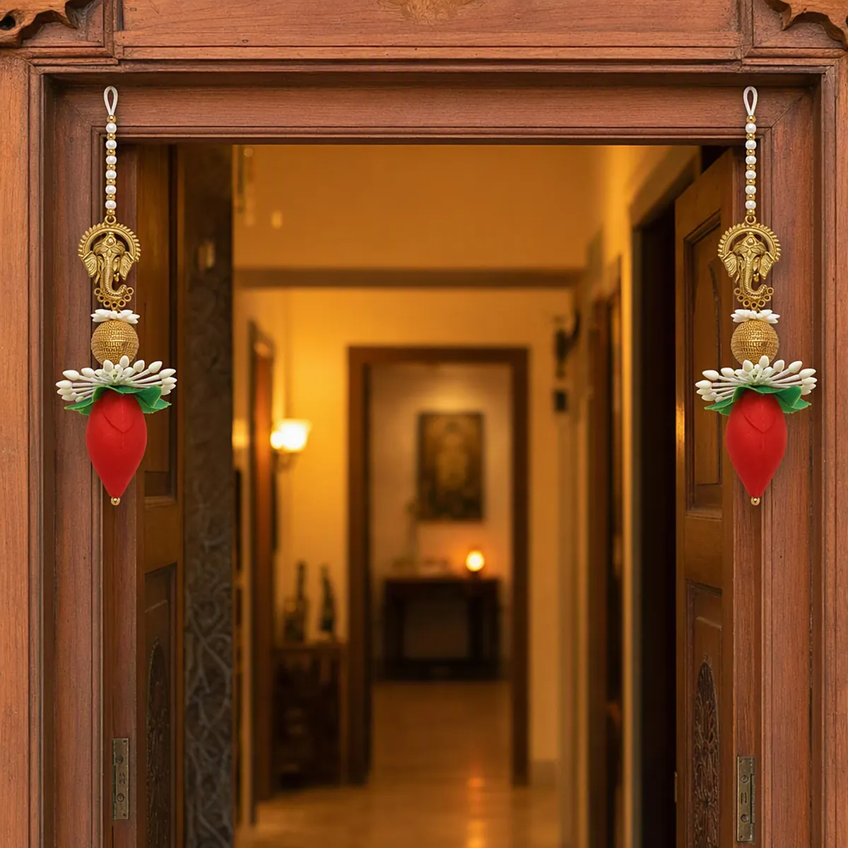 A doorway framed by Ganesh ji latkans with red lotus buds, lamps glowing down the hall